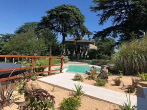 een zwembad in een tuin met een hek en planten bij Grande maison en pierre avec piscine, sauna et jacuzzi in Madaillan