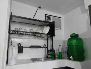 a kitchen counter with a sink and a green container at Vin's Place Rentals - Studio Unit in Tagum