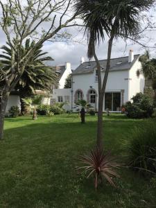 a white house with a palm tree in a yard at Le Récif, maison indépendante Corniche de la mer in Concarneau