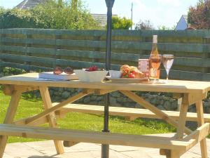 uma mesa de piquenique de madeira com comida e vinho em Converted Barn Near Porthleven em Breage