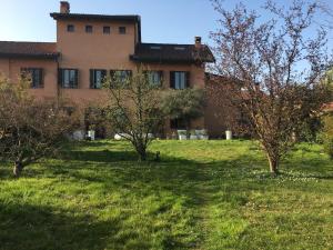 una casa en un campo con árboles delante en Cascina Torriggio Estates, en Rozzano
