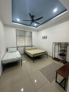 een kamer met 2 bedden en een plafondventilator bij Eco Homestay Ipoh in Simpang Pulai