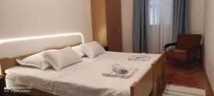 una camera da letto con un letto con lenzuola bianche e una sedia di Studio Apartment Lile a Trstenik