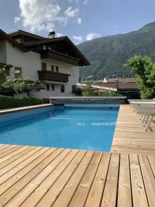 una piscina con terrazza in legno e una casa di Garni & Residence Sonngart a Lagundo