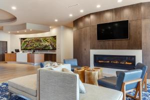 a living room with a fireplace and a tv at Cambria Hotel Spokane Airport in Spokane