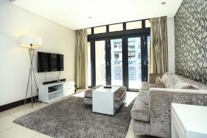 a living room with a couch and a tv at Melrose Arch Luxury Apartment - WITH GENERATOR in Johannesburg
