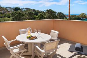 uma mesa branca com cadeiras e copos de vinho numa varanda em Extraordinary Villa on an elevated position in Quinta do Lago em Quinta do Lago