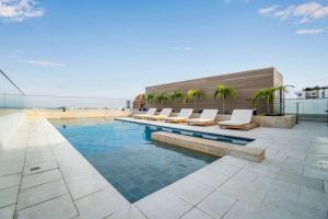 H602 - Cozy Garden View, Fast WiFi & Rooftop Pool في كالي: مسبح مع كراسي الصالة والنخيل