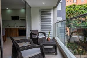 H602 - Cozy Garden View, Fast WiFi & Rooftop Pool في كالي: بلكونه فيها كرسيين وطاولة ومطبخ