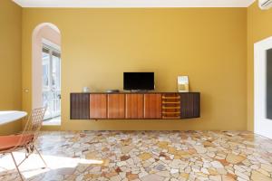 ミラノにあるBrera Apartments in Porta Ticineseの黄色の壁にテレビ付きのリビングルーム