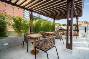 H602 - Cozy Garden View, Fast WiFi & Rooftop Pool في كالي: فناء فيه طاولات وكراسي تحت البرغولية