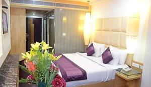ein Schlafzimmer mit einem großen weißen Bett mit lila Kissen in der Unterkunft HOTEL CRORE GRAND BHARAT STAY in Neu-Delhi