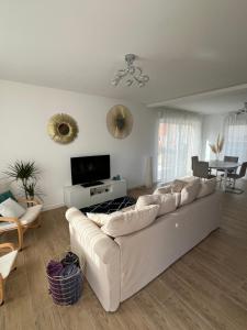 ein Wohnzimmer mit einem weißen Sofa und einem TV in der Unterkunft Superbe Maison avec jardin in Bezannes-les-Reims