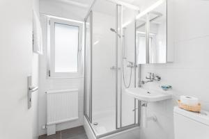 uma casa de banho branca com um chuveiro e um lavatório. em Sallaz Residence by Homenhancement em Lausanne