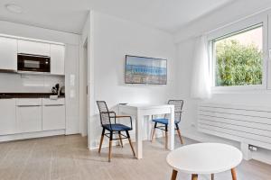cocina blanca con mesa blanca y sillas en Sallaz Residence by Homenhancement, en Lausana