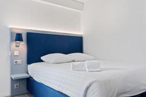 Cama blanca con cabecero azul y almohadas blancas en Sallaz Residence by Homenhancement, en Lausana