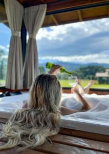 a woman laying in a tub with a glass of wine at Morada da Paz in Aguas Mornas