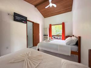 a bedroom with two beds and a window with red curtains at Pousada J Country in Sana