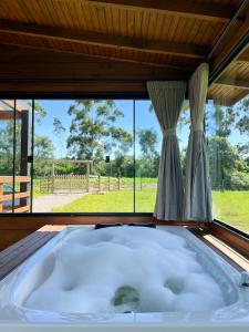 eine große Badewanne in einem Zimmer mit Fenster in der Unterkunft Morada da Paz in Aguas Mornas