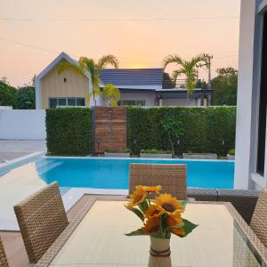 a table with chairs and a vase with flowers on it at 22Pool villa Hua-Hin in Hua Hin