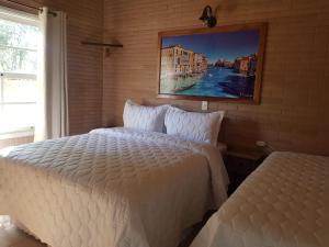 a bedroom with two beds and a painting on the wall at Villagio Matera in Campo Largo