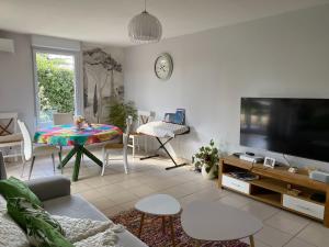 - un salon avec un canapé, une télévision et une table dans l'établissement les Jardins du Ventoux, à Carpentras