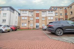 a parking lot with cars parked in front of a building at Park View-modern 2 bed apartment in Motherwell