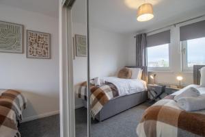 a bedroom with two beds and a mirror at Park View-modern 2 bed apartment in Motherwell