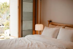 ein Schlafzimmer mit einem weißen Bett und einem Fenster in der Unterkunft Gyeongju Hanok Sohwa in Gyeongju