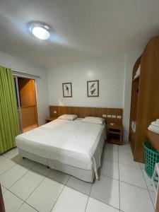1 dormitorio con cama blanca y cortina verde en Flat Golden Dolphin Grand Hotel - Quarto e Sala Com Roupa de Cama e Banho - Piscinas 24h en Caldas Novas