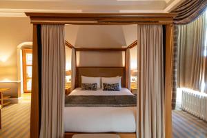 a bedroom with a canopy bed with white sheets and pillows at Dunkeld House Hotel in Dunkeld