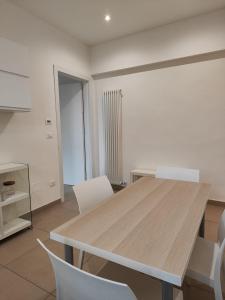 uma sala de jantar com uma mesa de madeira e cadeiras brancas em Casa nel Parco em Bolonha