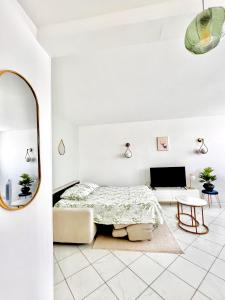 ein weißes Schlafzimmer mit einem Bett und einem Spiegel in der Unterkunft Appartement face gare / centre in Argenteuil
