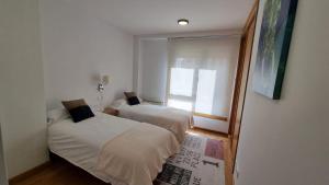 2 Betten in einem kleinen Zimmer mit Fenster in der Unterkunft Piso en el centro para 6 personas en Vilagarcia in Vilagarcia de Arousa