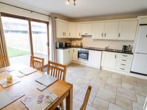 a kitchen with white cabinets and a table with chairs at Sea Breeze Holiday Home in Enniscrone