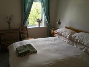 a bed with a towel on it with a window at Dryden Gardens in Edinburgh
