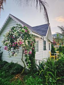 mały domek z różowymi kwiatami przed nim w obiekcie Larita Đồi Cỏ Mơ w mieście Hòa Bình