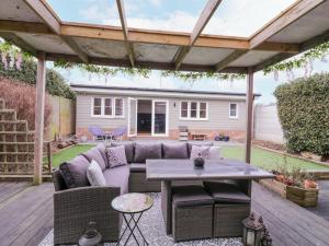 a patio with a couch and a table on a deck at Hide and Sleep in Walton-on-the-Naze