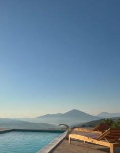 a pool with chairs and mountains in the background at Zemunice Knezevic in Banja Luka