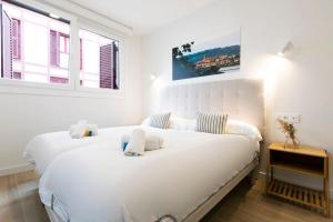 a white bedroom with two beds and a window at Portuko. Basquenjoy in Hondarribia