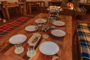a wooden table with plates and wine glasses on it at Alma Hotel Campestre in Santa Elena