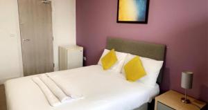 a bedroom with a white bed with yellow pillows at Sandal Park View - Duplex Relocations in Wakefield