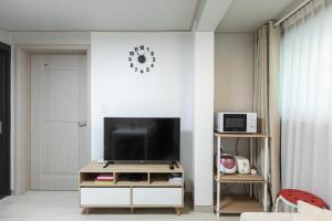 a living room with a television on a white wall at Laon House Yeonnam in Seoul