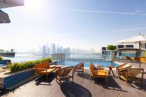 a patio with chairs and tables and a pool at Modern 1 bedroom at Palm Jumeirah in Dubai