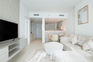 a white living room with a white couch and a tv at Modern 1 bedroom at Palm Jumeirah in Dubai