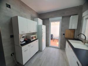 eine Küche mit weißen Schränken und einer Mikrowelle in der Unterkunft Apartamento a 100 metros de la playa in Piles