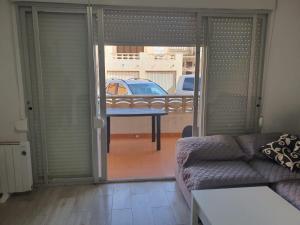ein Wohnzimmer mit einem Sofa und einer Glasschiebetür in der Unterkunft Apartamento a 100 metros de la playa in Piles