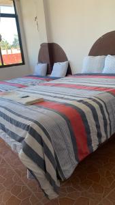 a large bed with a striped blanket on it at Hotel Puerto Real in Paraíso
