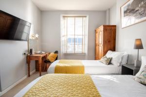 a hotel room with two beds and a desk at Bendene Townhouse - Exeter in Exeter