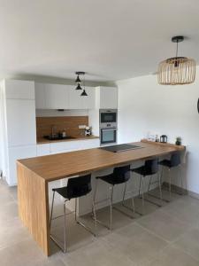 a kitchen with a wooden counter with bar chairs at Appartement Le Cocoon in Le Cheylard +1 photo